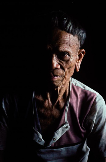 An elder from the indigenous Kelabit tribe in Sarawak sits in a longhouse that was relocated to make way for the Bakun dam. The dam flooded 700 square kilometres (270 square miles) of rainforest and farms and displaced 10,000 people. Photo by Rod Harbinson. 