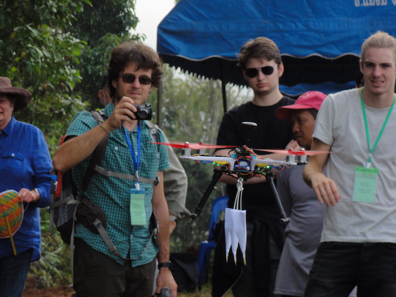 Onlookers watch a demonstration of a seed-dispersing drone, which can drop darts containing seeds. The demonstration took place during a workshop on automated forest restoration this fall in Thailand. Photo by S. Elliott. 