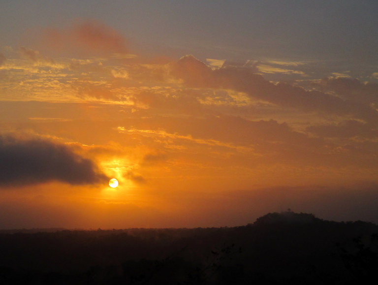 The sun rises over the seemingly endless jungle in Guatemala's Maya Biosphere Reserve. To the right, the top of the massive La Danta pyramid juts out above the canopy. Photo by Sandra Cuffe.