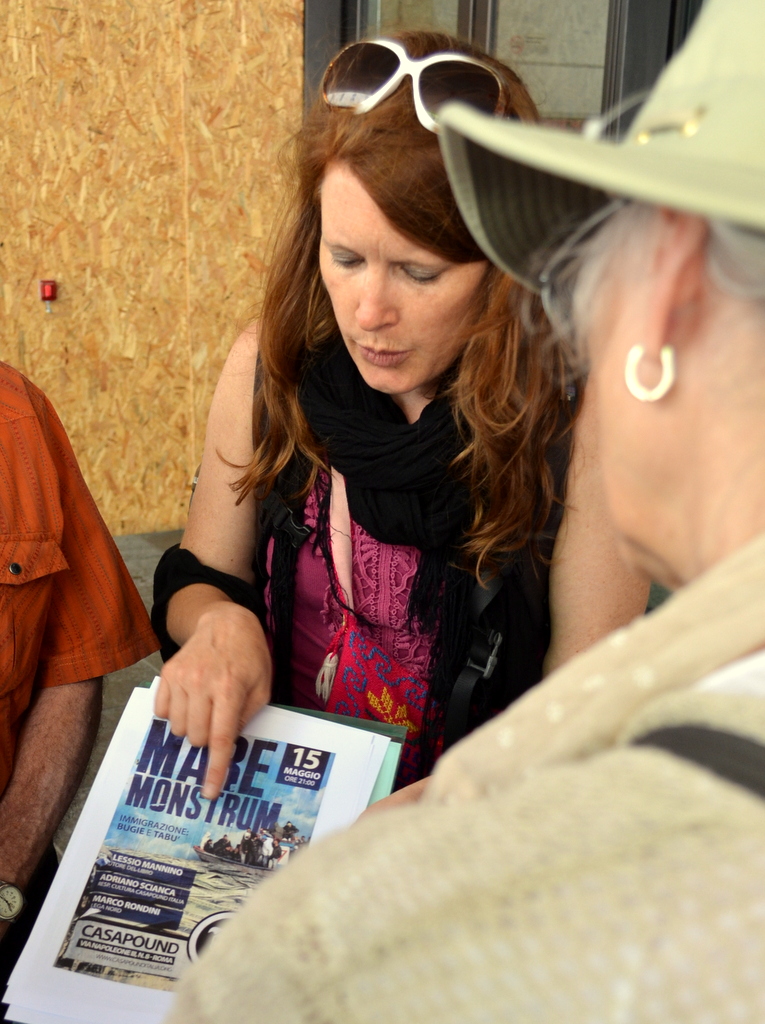JRS official Jill Drzewiecki shows Emmylou Harris a xenophobic poster seen around Rome. Photo by Justin Catanoso