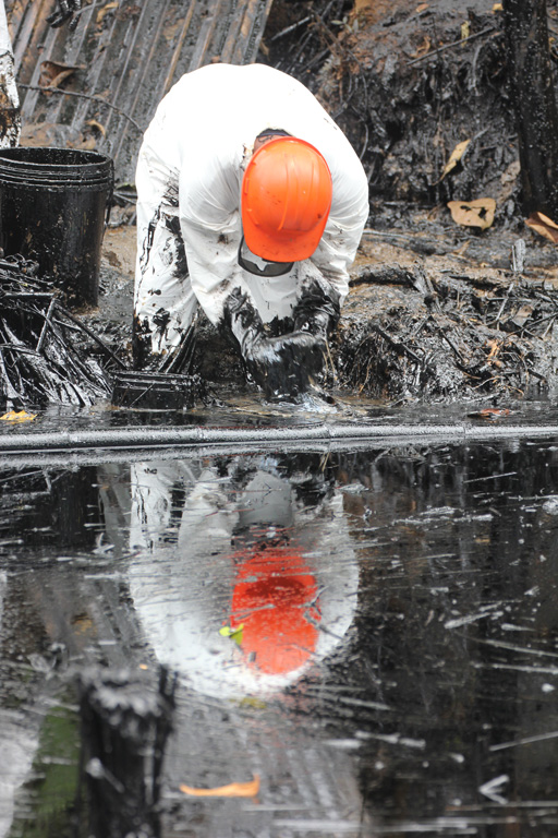 A cleanup worker scoops oily vegetation from a stream near a pipeline spill near the northern Peruvian town of Chiriaco. Photo by Barbara Fraser.
