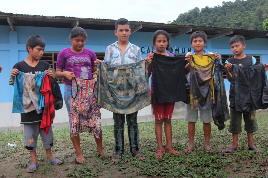 Niños en Nazaret, un pueblo en la confluencia del los ríos Chiriaco y Marañón al norte de Perú, muestran la ropa que llevaban cuando sacaban petróleo del río Chiriaco después del derrame del oleoducto. Foto de Barbara Fraser.