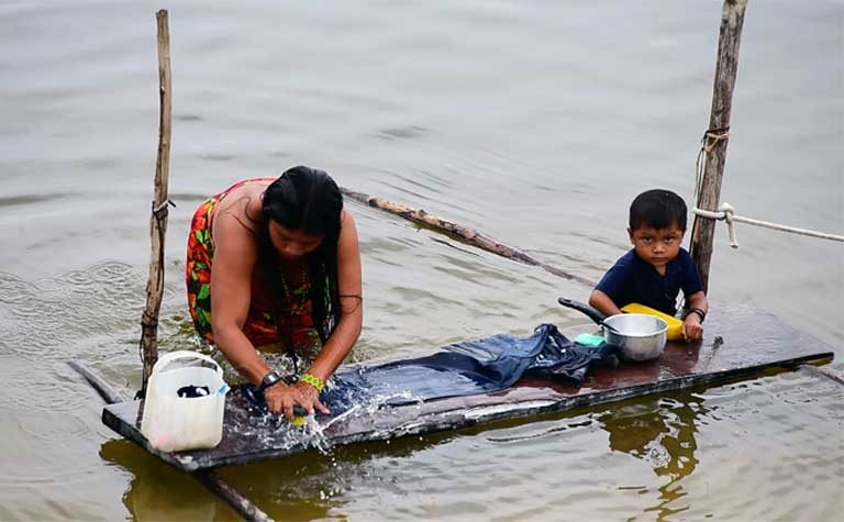 An indigenous woman washing a carpet in the Teles Pires River. The Munduruku and other indigenous groups rely on the river for everything — for work and play, as livelihood and a transportation corridor. The Teles Pires dam has negatively impacted many of these activities. Photo by Thais Borges